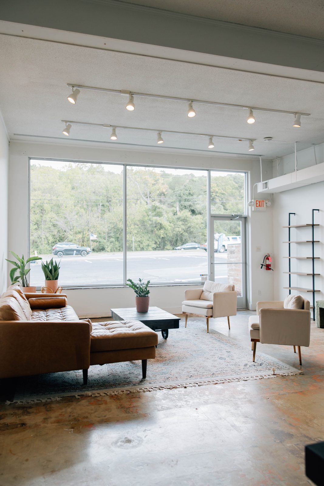 The studio main room with track lighting, a leather sofa and a big window