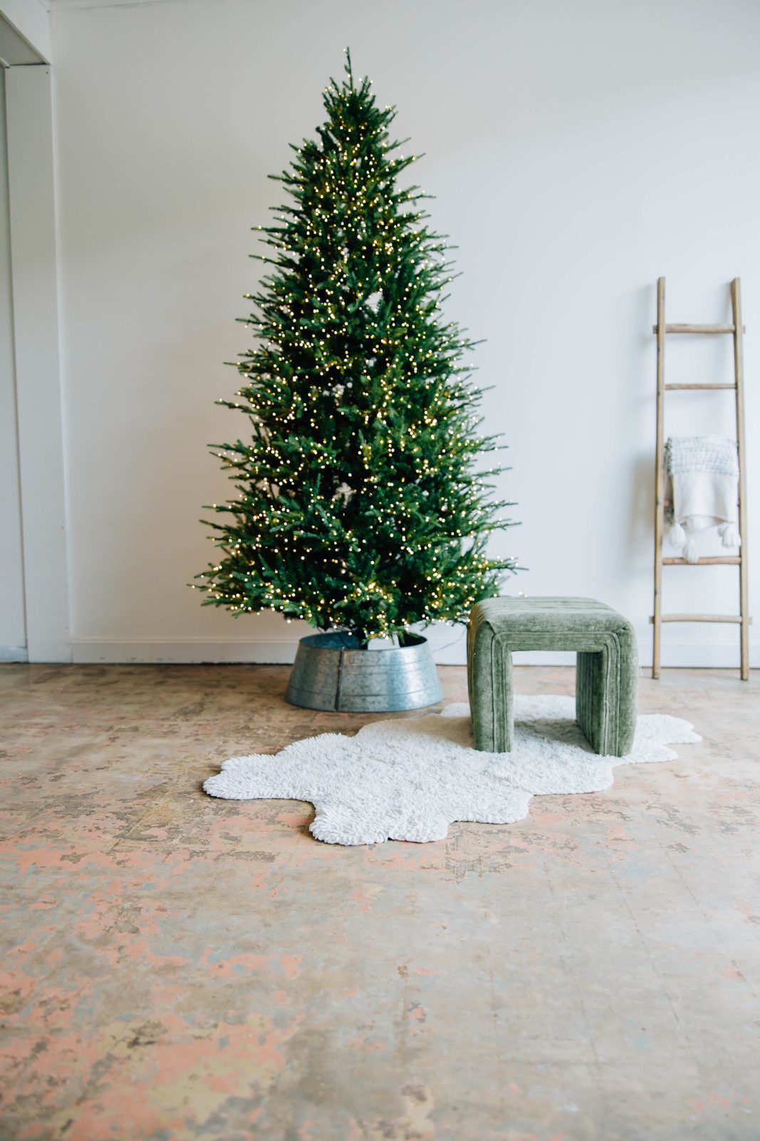 The Christmas tree set with a ladder, green stool and white rug in the studio
