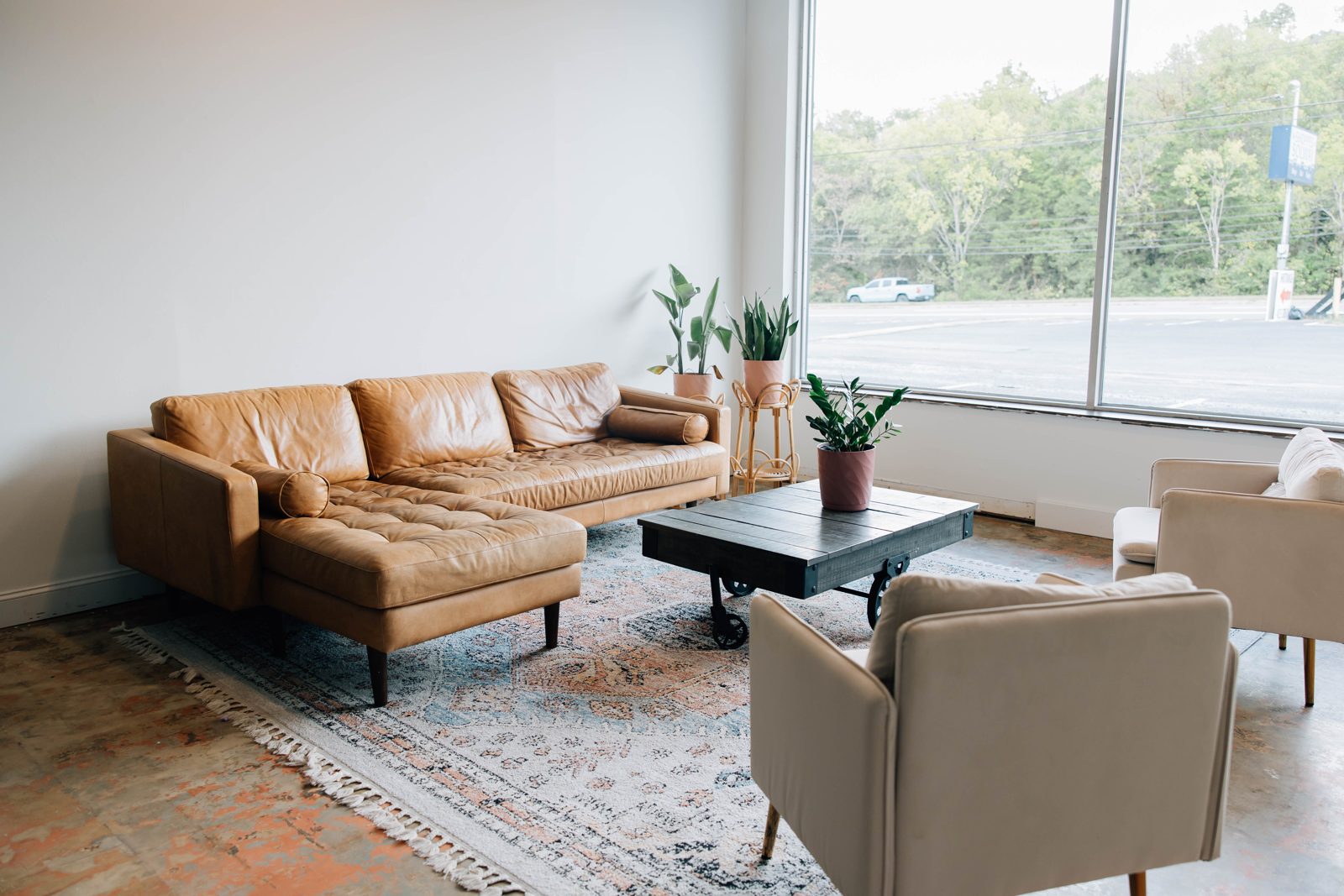 Trade House Studio main room with a leather sofa, armchairs and a large window